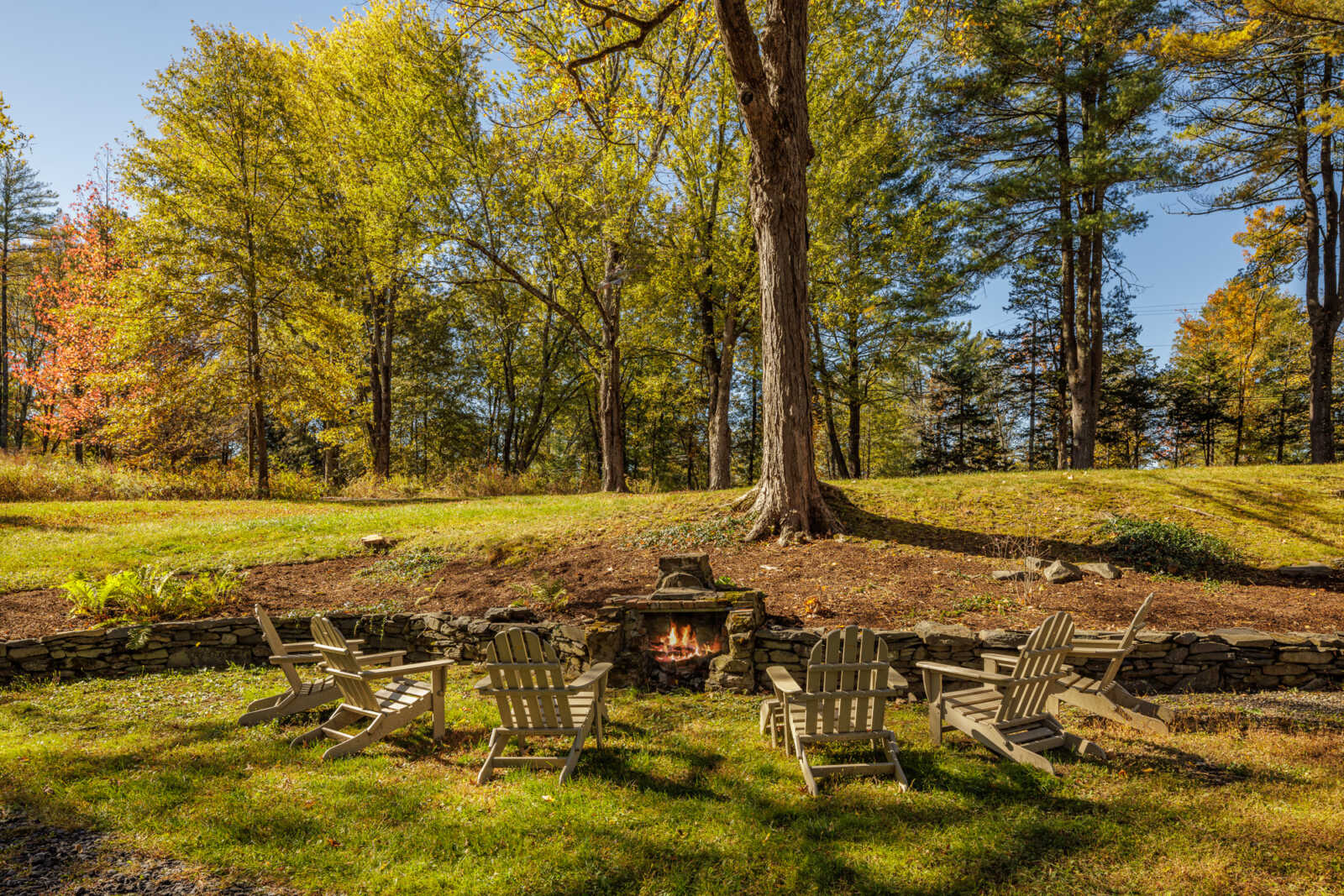 view of lawn with Adirondack chairs around a fire