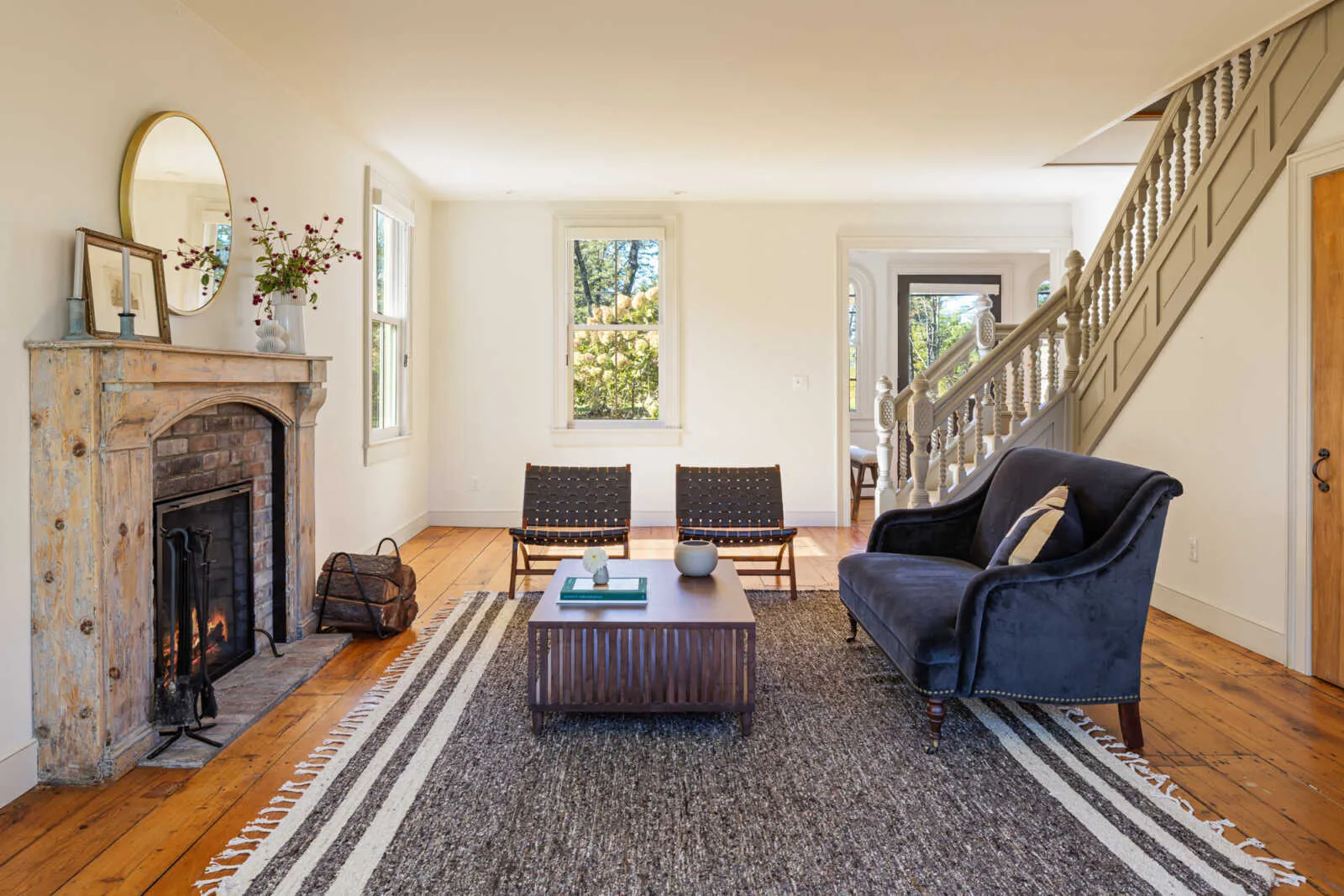 parlor with stone mantel, wide planked floorboards, view to central stair