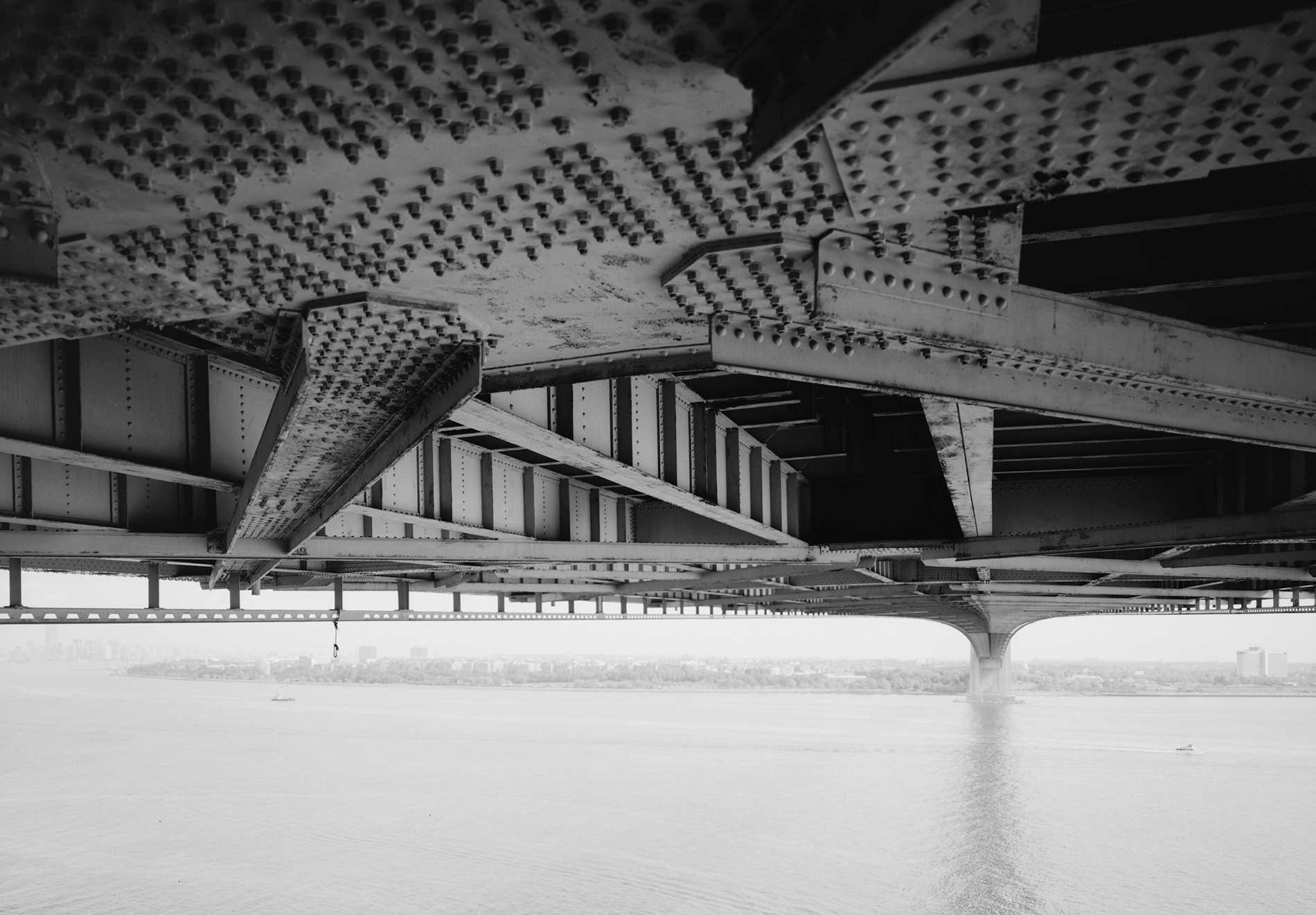 black and white photo showing a closeup of the steel work underneath the bridge