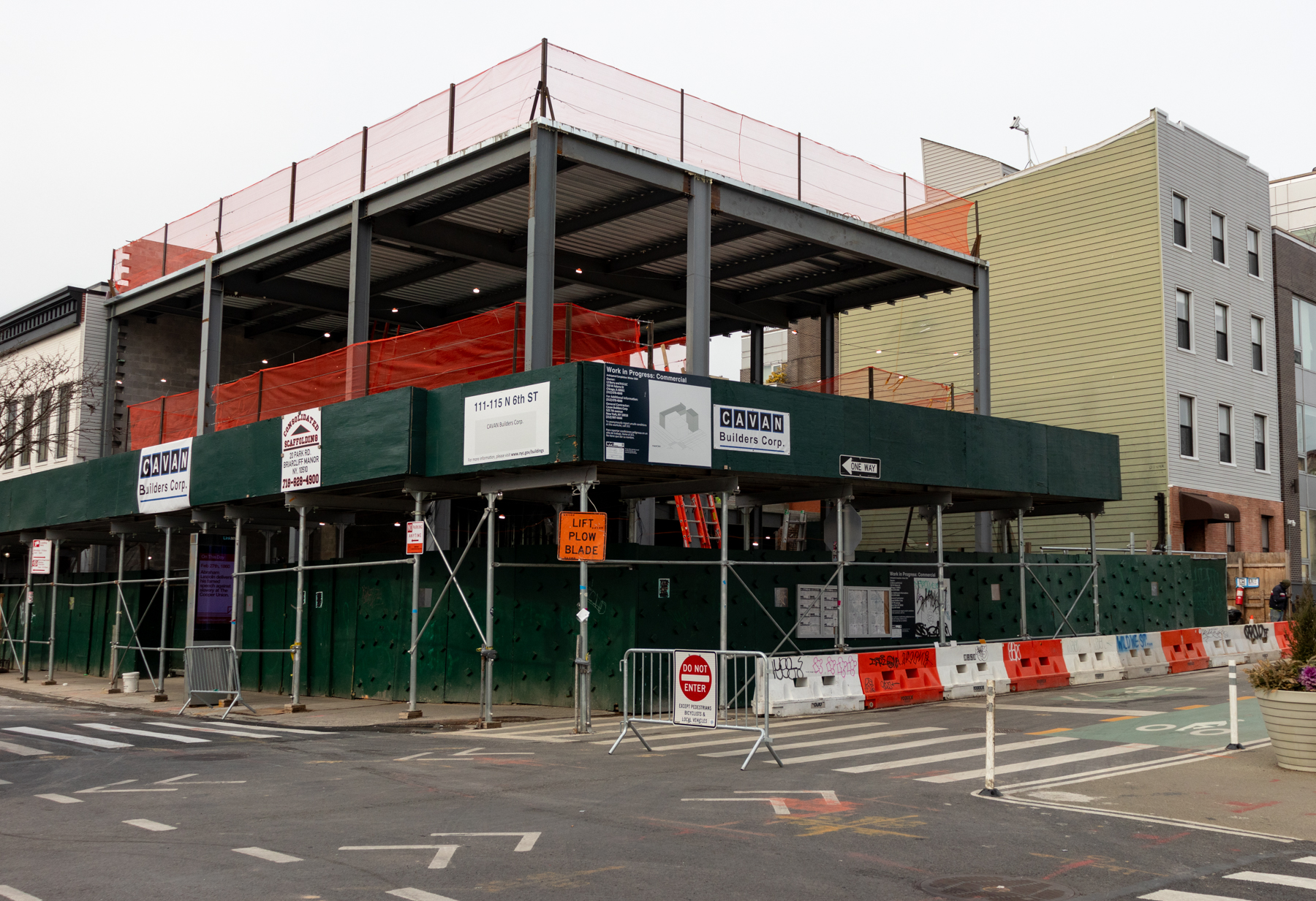 building rising behind a green construction fence