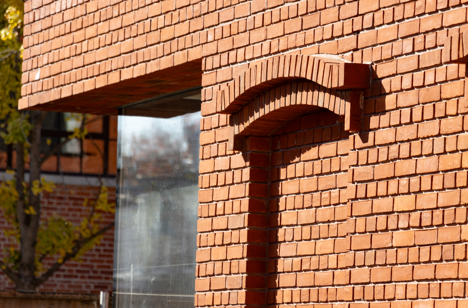 view behind the construction fence showing and inset glass window and a fake bricked-up window