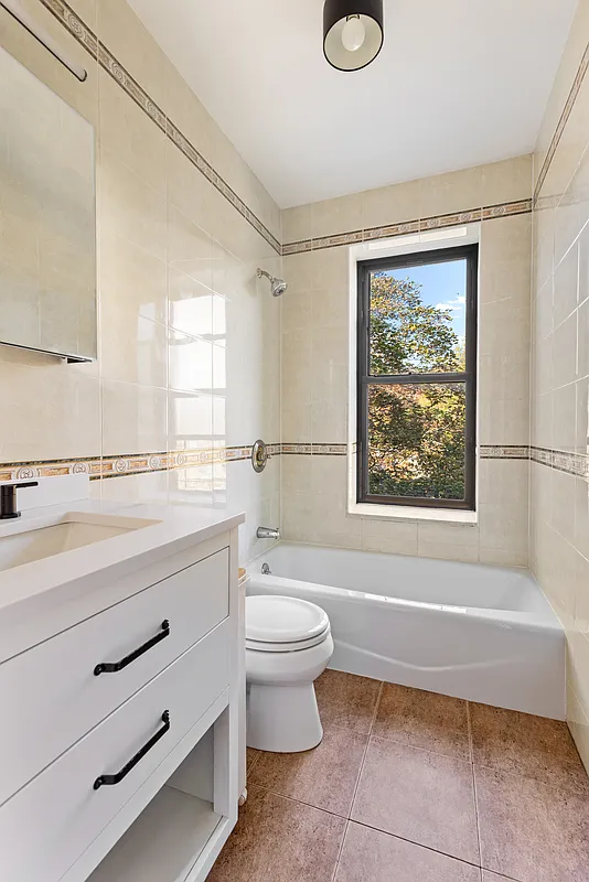 bathroom with beige wall and floor tiles and white fixtures