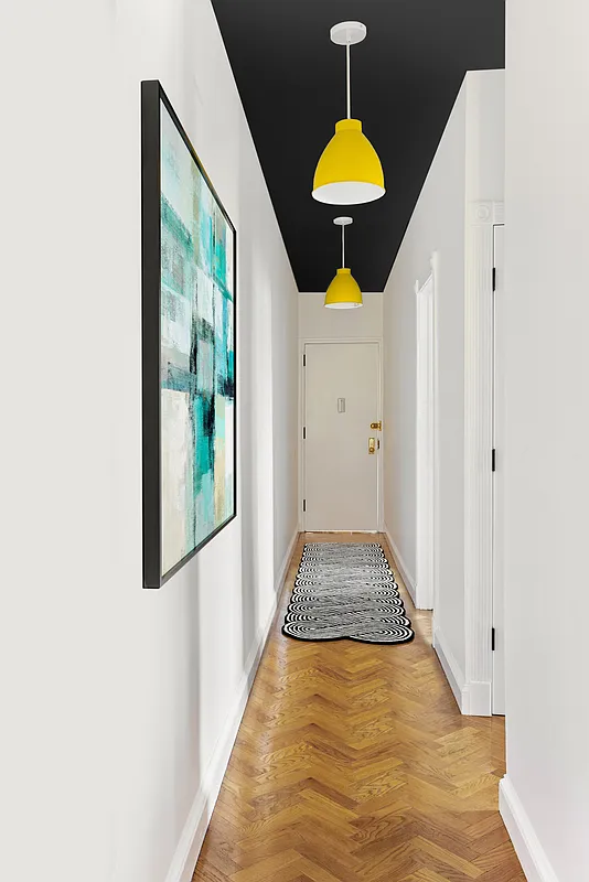 hallway with wood floor, dark ceiling and yellow pendants