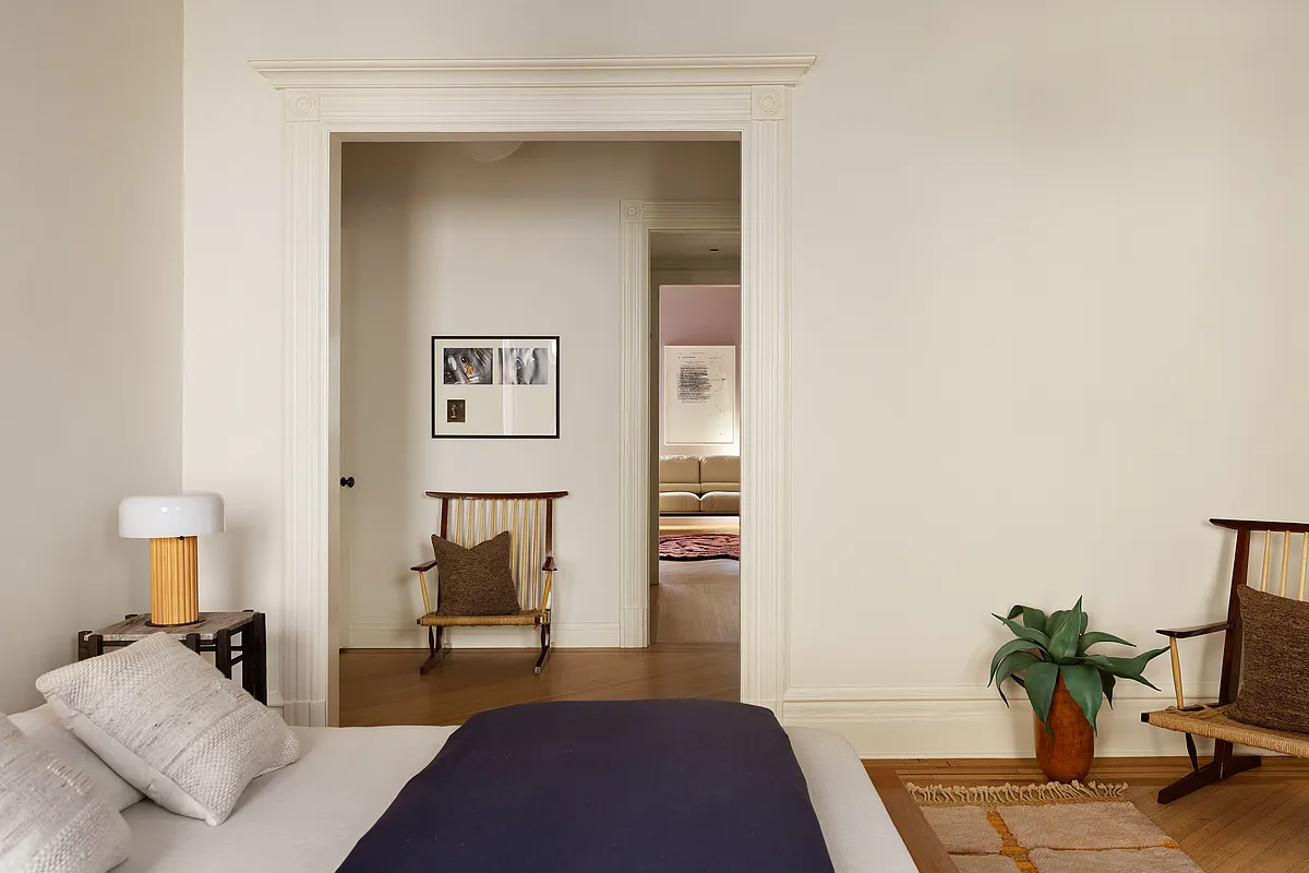 bedroom with cream walls, wood floor with view into dressing area