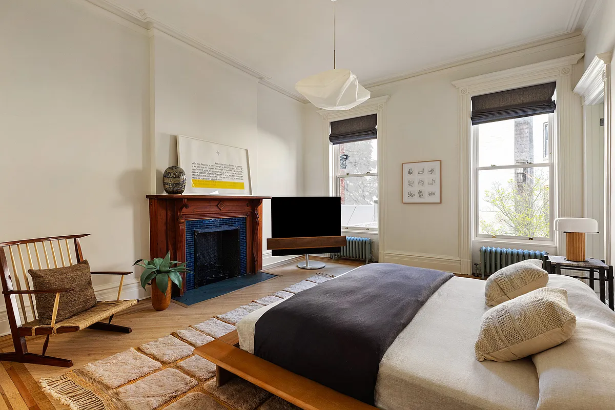 bedroom with wood floor, wood mantel with blue tile surround