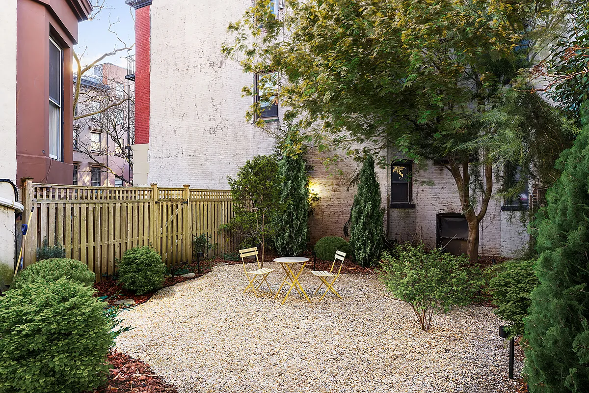 rear yard with gravel seating area ringed with shrubbery and planting beds