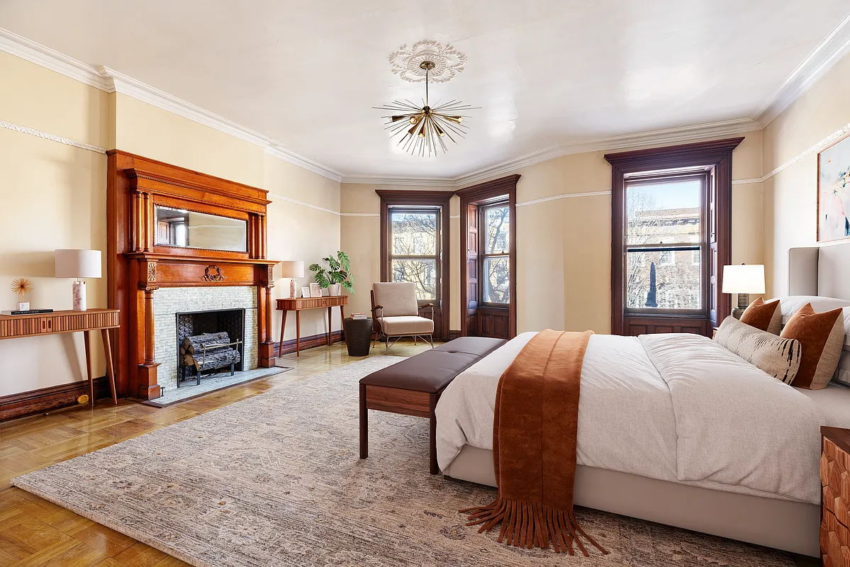 bedroom with interior shutters, mantel, wood floor